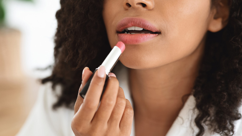 Woman putting on lipstick