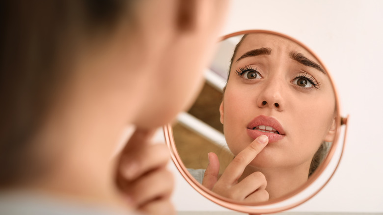 Woman looking at her lips in the mirror 