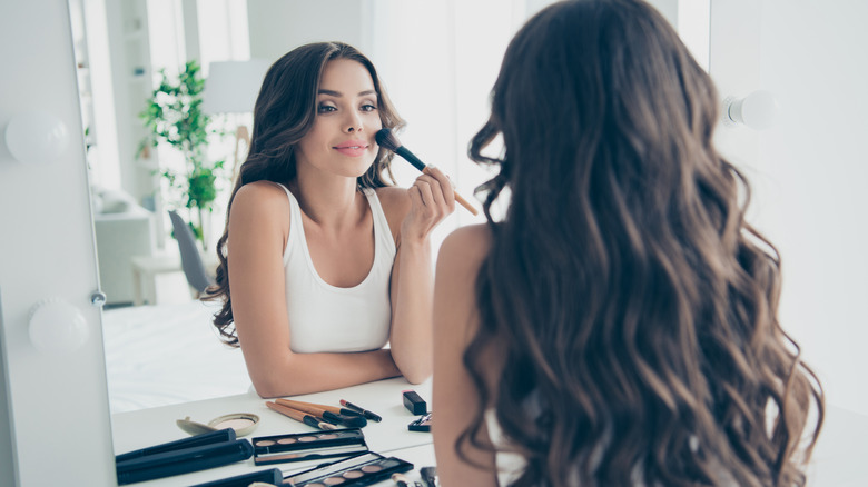 Woman seated at vanity, applying highlighter