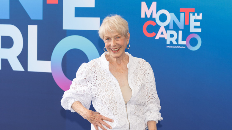 Karen Grassle smiles at a red carpet wearing a white top