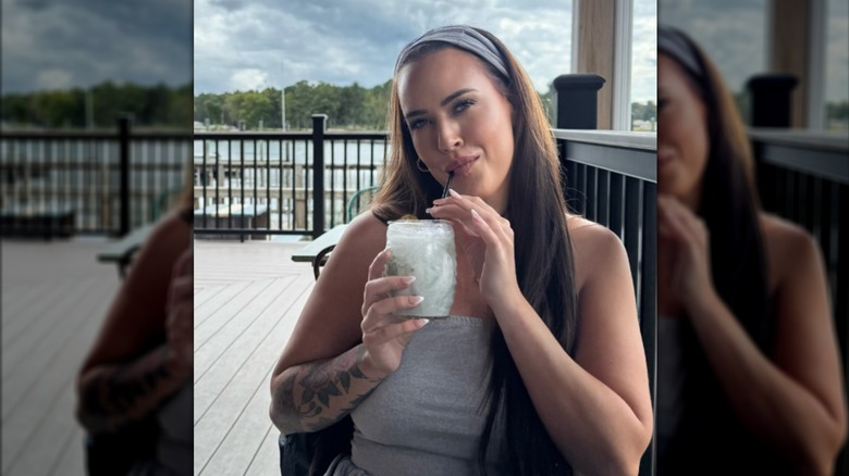 Chelsea Blackwell sips a beverage outdoor of a restaurant