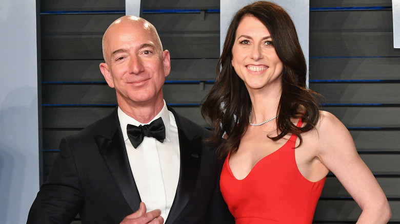 Jeff Bezos in a suit and MacKenzie Scott in a red dress posing for a picture at the 2018 Vanity Fair Oscar Party