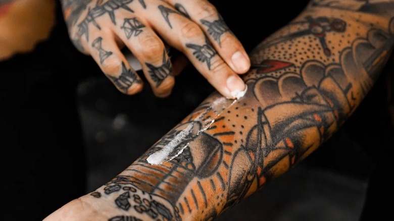 Person applying tattoo balm on forearm