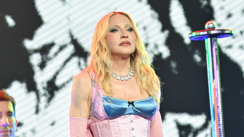 Madonna poses on stage in a pink-and-blue corset top