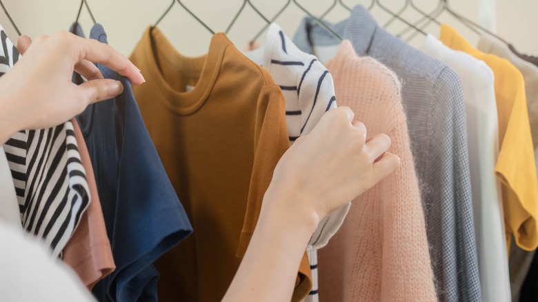 Closeup of women's hands rifling through closet