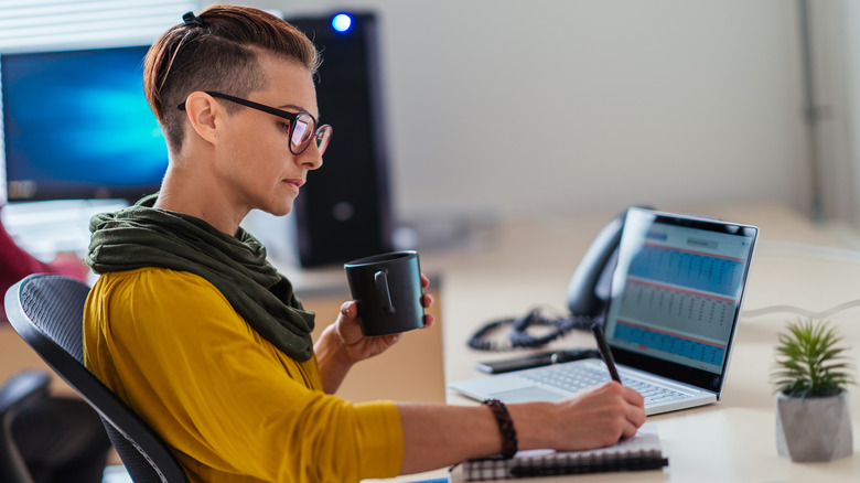 Woman working at desk holding coffee