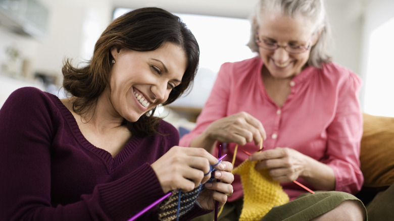 Two women knit together 