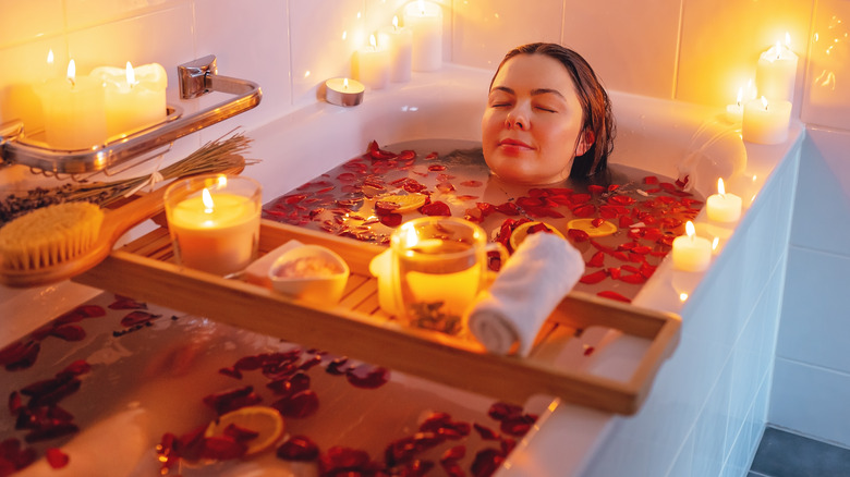 woman taking bath with candles and flowers
