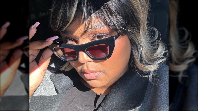 Lizzo posing with a malt shop bob and glasses