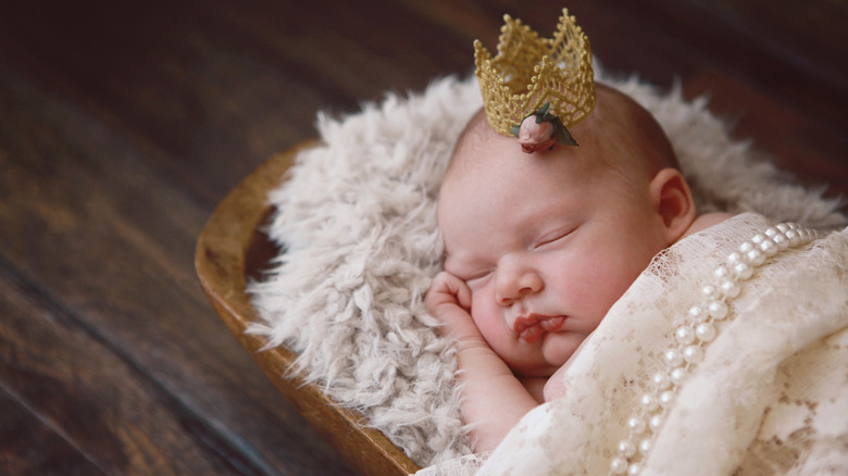 Baby girl sleeping with a tiara and a pearl blanket