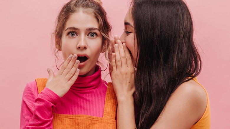 two young woman gossiping together