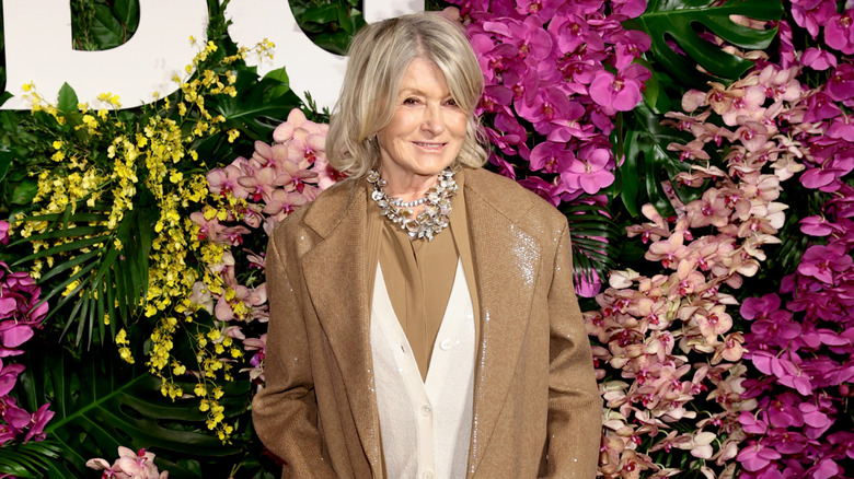 Martha Stewart posing at an event in 2026 wearing a beige-and-white outfit with a statement necklace.