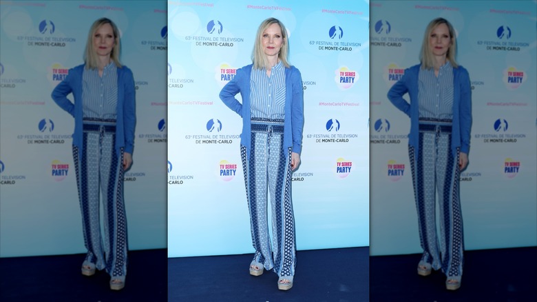 Melissa Sue Anderson poses wearing a striped shirt, a blue cardigan, and patterned blue trousers