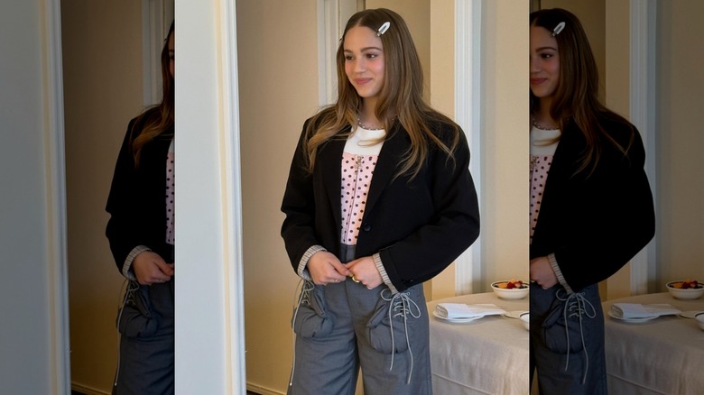 Skywalker Hughes wearing a black jacket and polka-dot shirt with gray pants and clips in her hair.