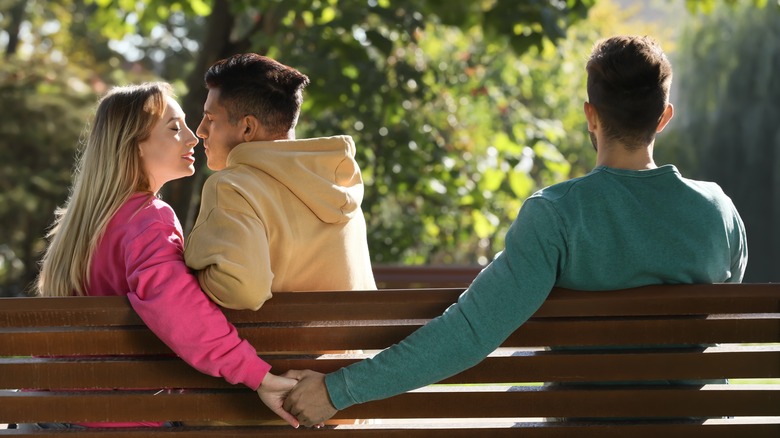 Three people sitting on bench