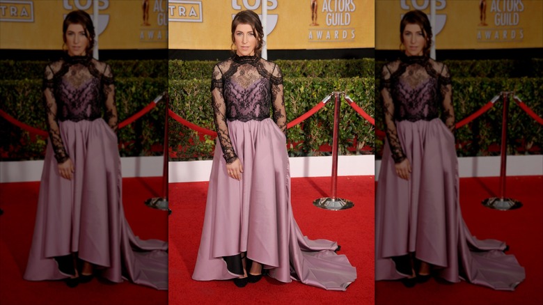 Mayim Bialik poses wearing a mauve dress with black lace.