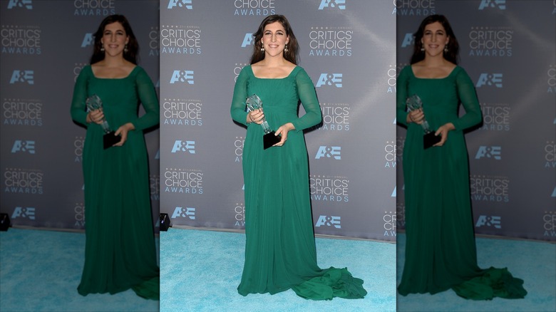 Mayim Bialik poses wearing an emerald green gown