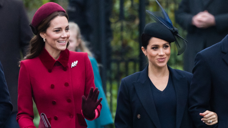 Meghan Markle, wearing black, and Kate Middleton, wearing red, pictured together arriving at a Christmas Day church service.