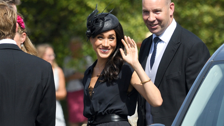 Meghan Markle wears a black blouse and hat