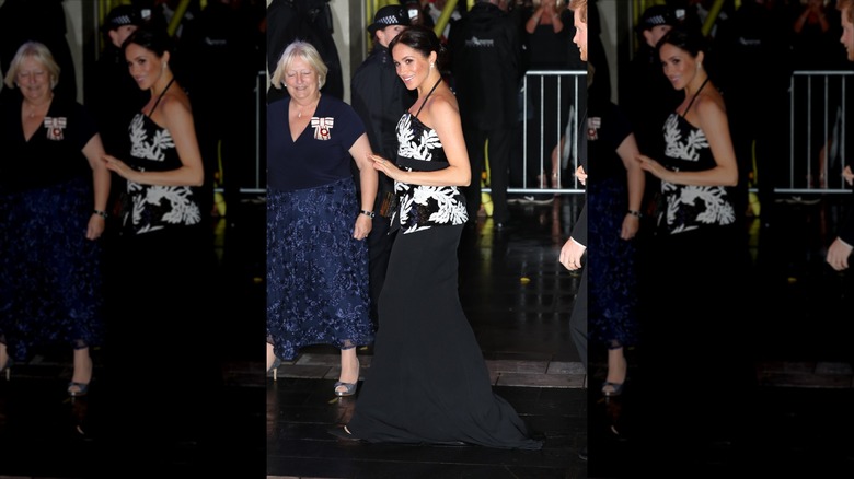 Meghan Markle walks wearing a black maxi skirt and a monochrome sequin top