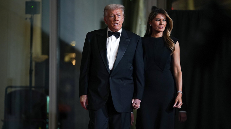 Donald and Melania Trump walking hand in hand in black tie attire