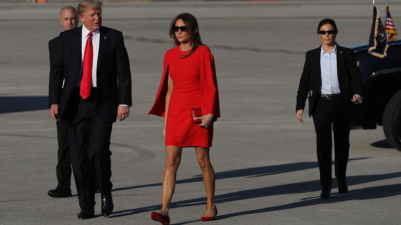 Melania Trump wearing a red mini dress while walking with Donald Trump