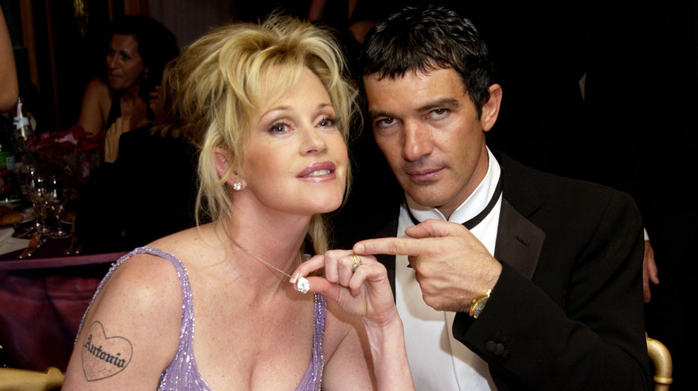 Melanie Griffith (L) holds a crystal necklace next to Antonio Banderas wearing a tuxedo