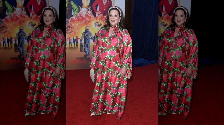 Melissa McCarthy smiling while wearing a dress with a rose print