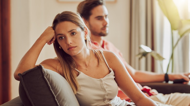 Unhappy woman turns away from man on sofa