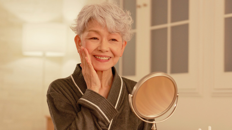 A woman holding her head as she looks into the mirror
