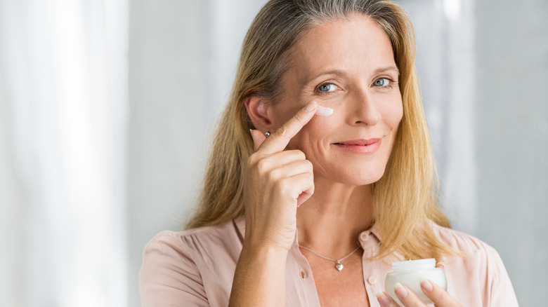 An older woman applying moisturizer