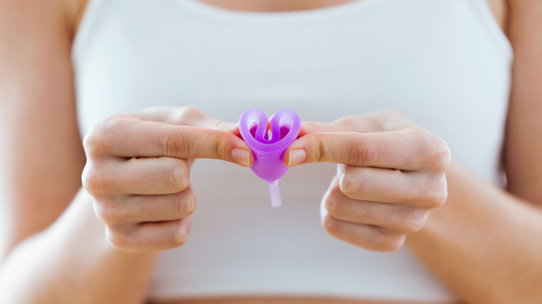 woman squeezes menstrual cup