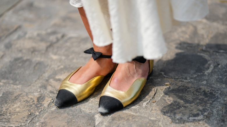 woman wearing gold ballet flats