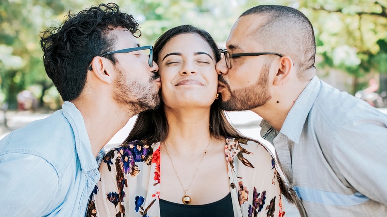 two men kissing woman