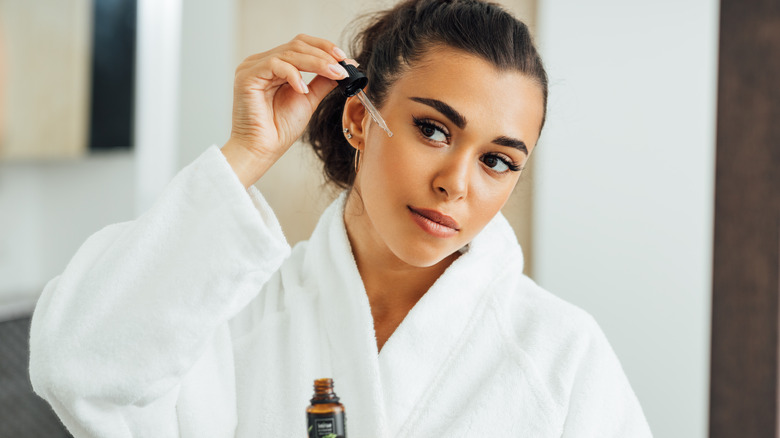 woman applying serum to face