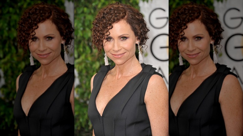 Minnie Driver posing at the Golden Globes in a black dress with her hair tightly curled and pulled back.