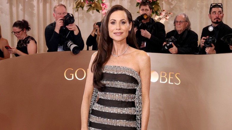 Minnie Driver posing on the red carpet in a black-and-silver striped dress.