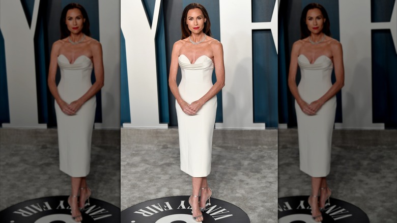 Minnie Driver posing at an event wearing a simple white strapless dress.