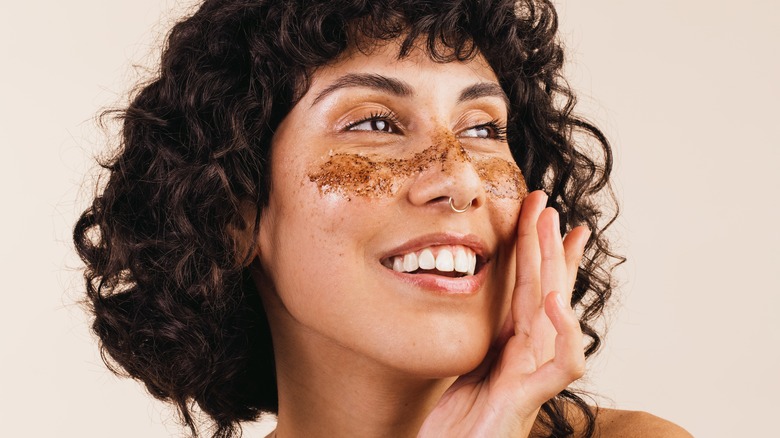 Woman applying a scrub to her face.