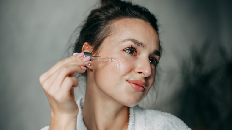 woman applying serum on cheek 