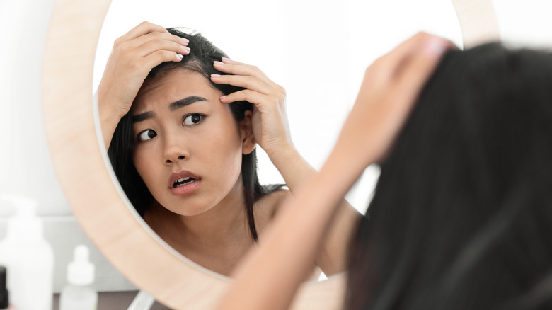 woman looking in mirror at scalp