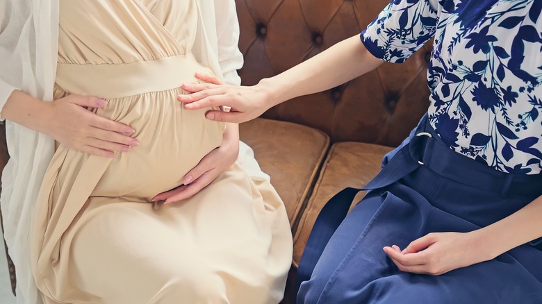 Friend touching pregnant belly