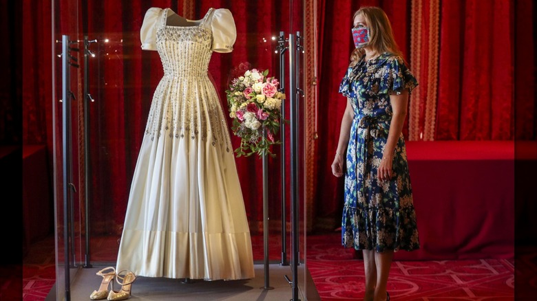 Princess Beatrice poses next to her wedding dress on display at Windsor Castle.