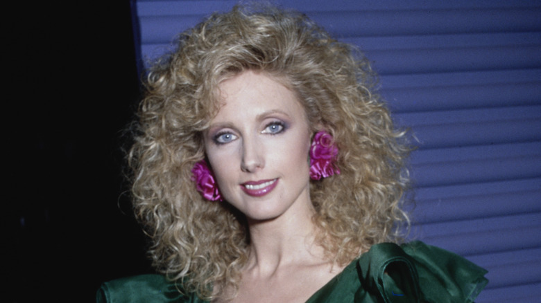 Morgan Fairchild at an event wearing a green dress and large pink earrings.