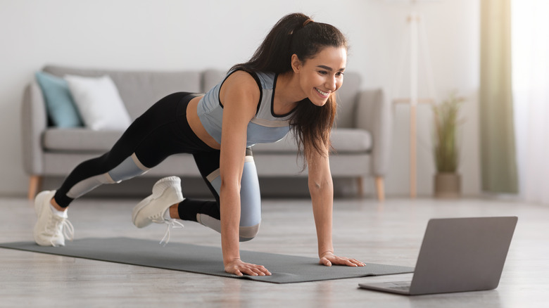 Woman exercising while looking at computer
