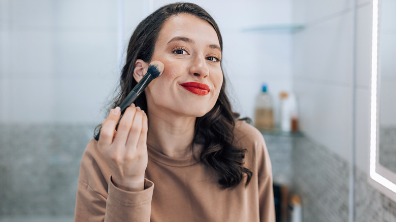 Woman applying makeup in mirror