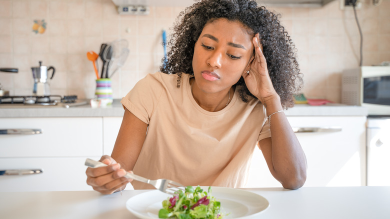 unhappy woman eating salad