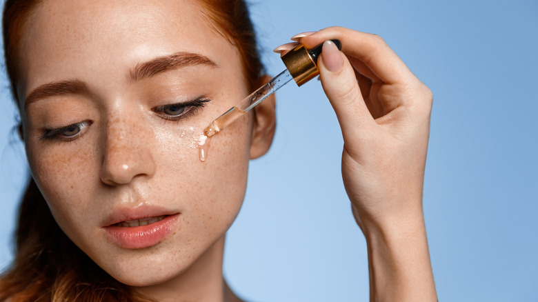 Woman applying face serum.