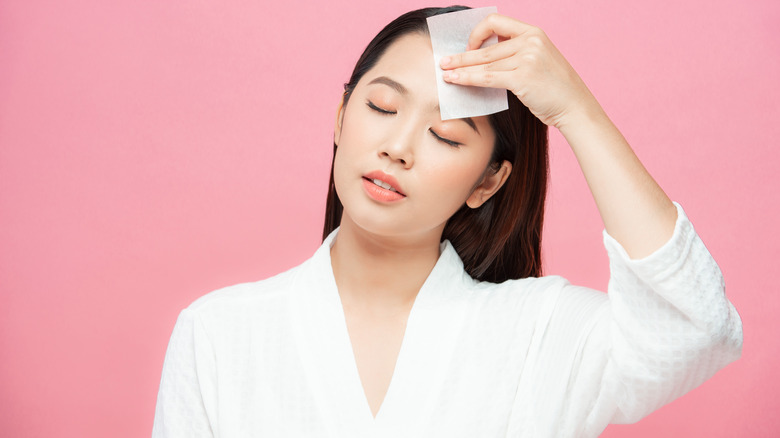 woman blotting oil on face