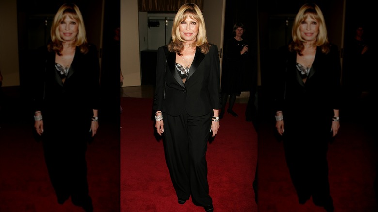 Nancy Sinatra at a red carpet event wearing an all-black outfit with her hair down.